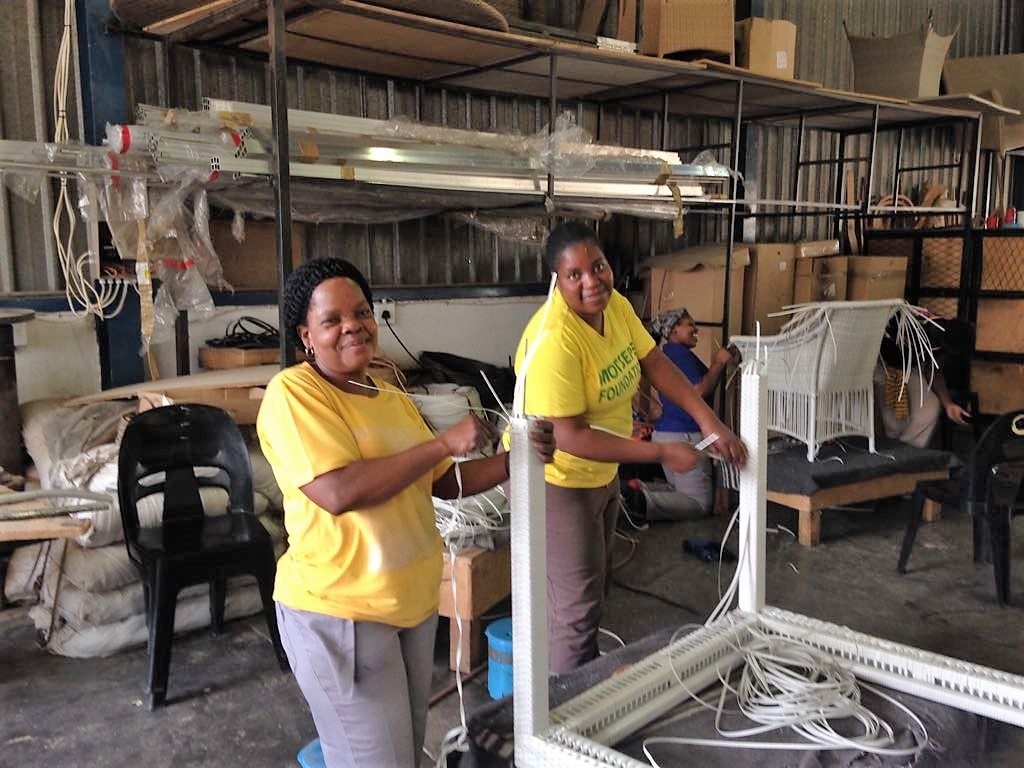 Two happy ladies weaving the Malindii dining table